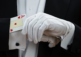 A magician hiding a card up the sleeve of his tuxedo