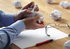 A frustrated man crumpling up paper drafts of writing