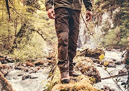A man walking on a log over a stream