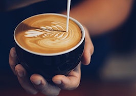 A barista pouring latte art into a latte