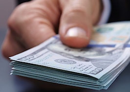A man handing a stack of $100 bills to an unseen person