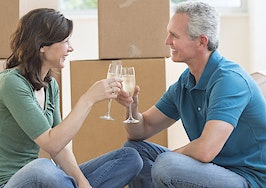 A couple sharing a champagne toast on the floor in their new house