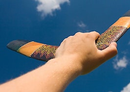 A hand holding a boomerang, preparing to throw