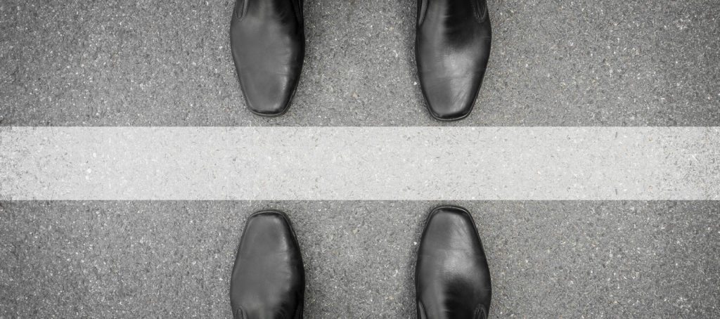 Two men standing on either side of a line on the ground