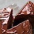 A piece of chocolate cake being removed from the whole