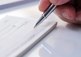 A man's hand writing a check