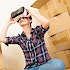 A woman looks through a virtual reality headset in the midst of boxes