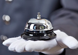 A white-gloved hand holding a concierge bell
