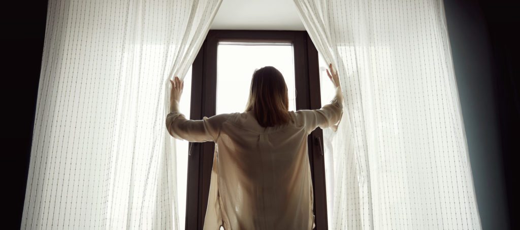 A woman opening the curtains