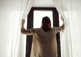 A woman opening the curtains